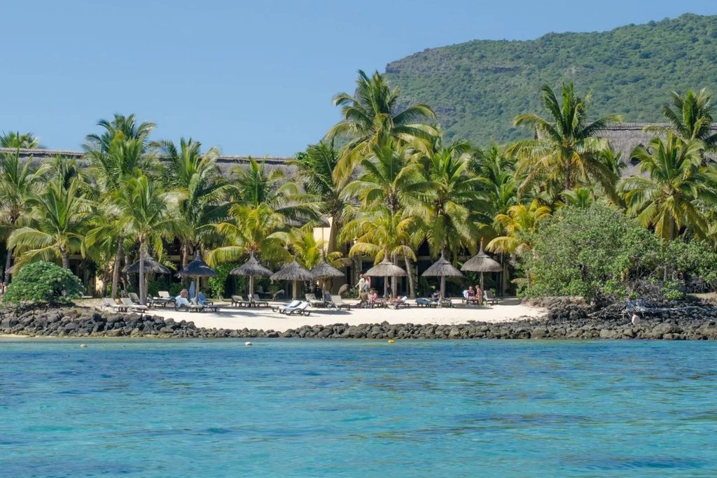 Strand met palmbomen en een resort op Mauritius, met helderblauwe zee op de voorgrond
